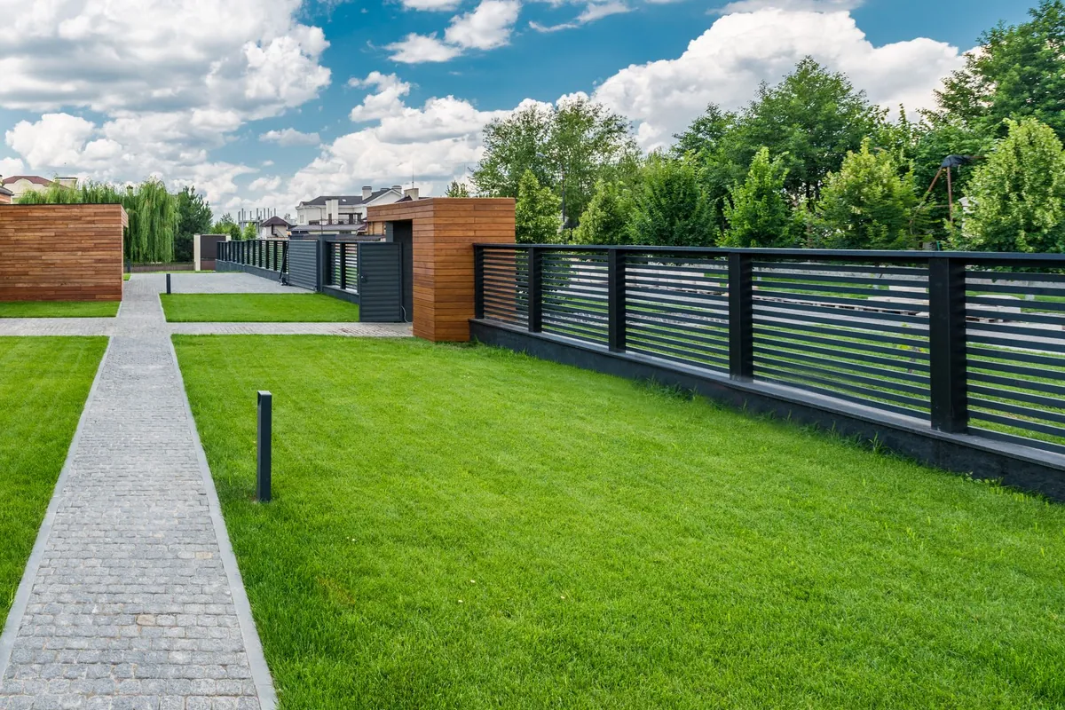 Modern horizontal slat fence along a new lawn