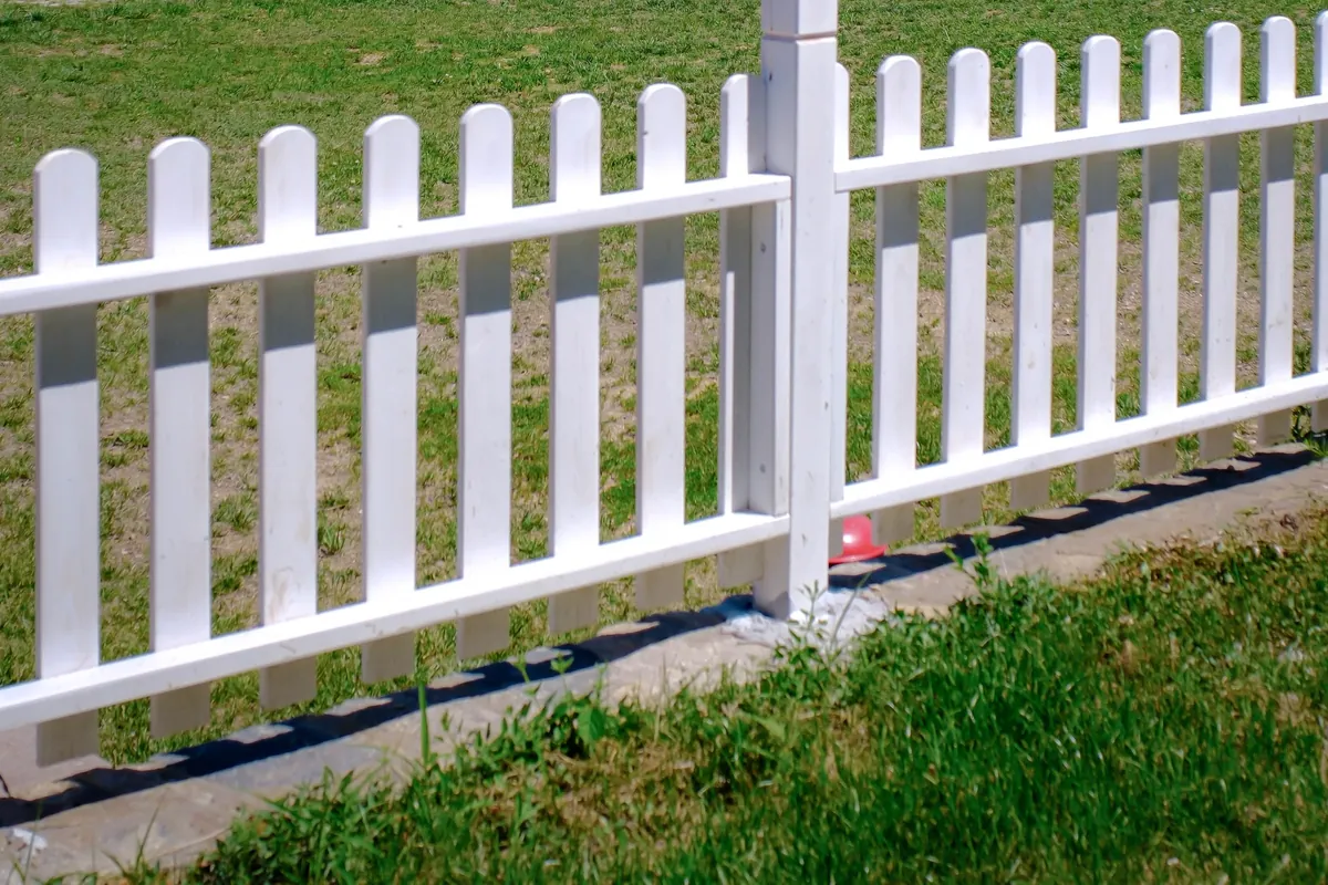 White vinyl picket fence on a grassy lot